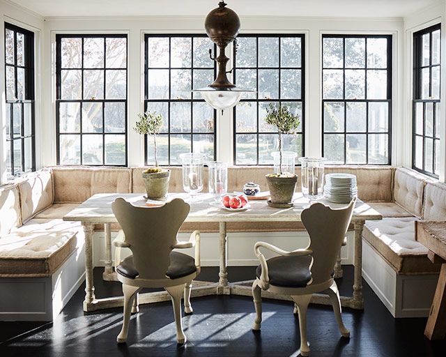 a dining room table with four chairs and a bench in front of the window,