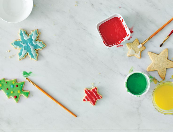 decorated cookies and icing on a table with paint, brushes and spoons next to them