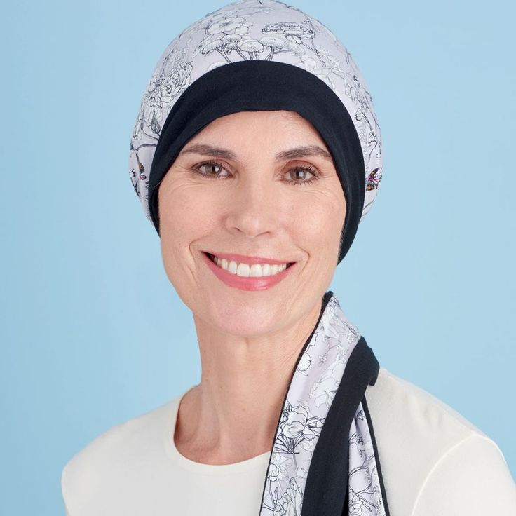 a woman wearing a head scarf and smiling at the camera with a blue background behind her