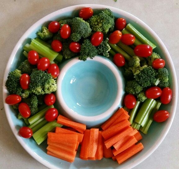 a white plate topped with carrots, broccoli and tomatoes next to a blue bowl