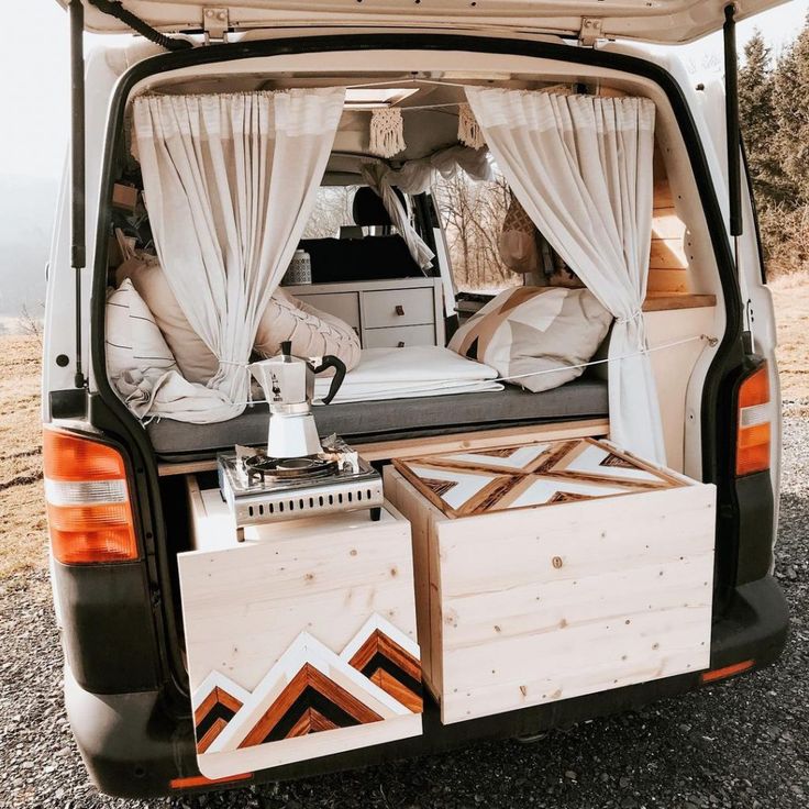 the back end of a van with two beds in it and curtains over the windows