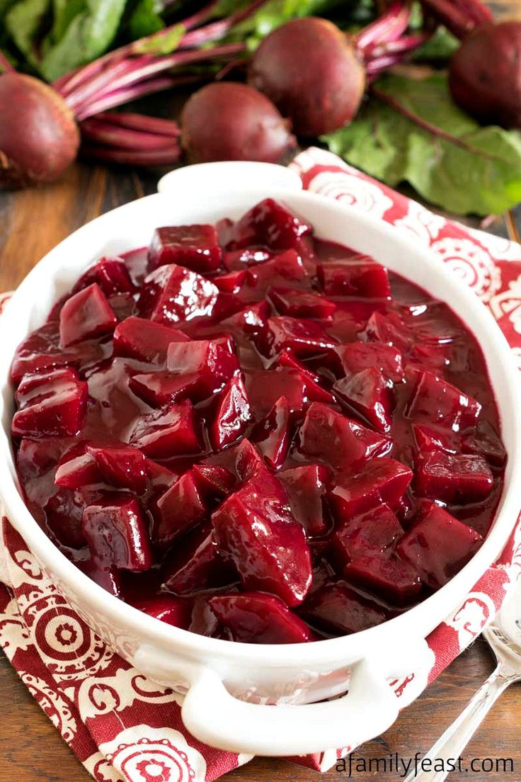 a bowl filled with beets sitting on top of a table next to other vegetables