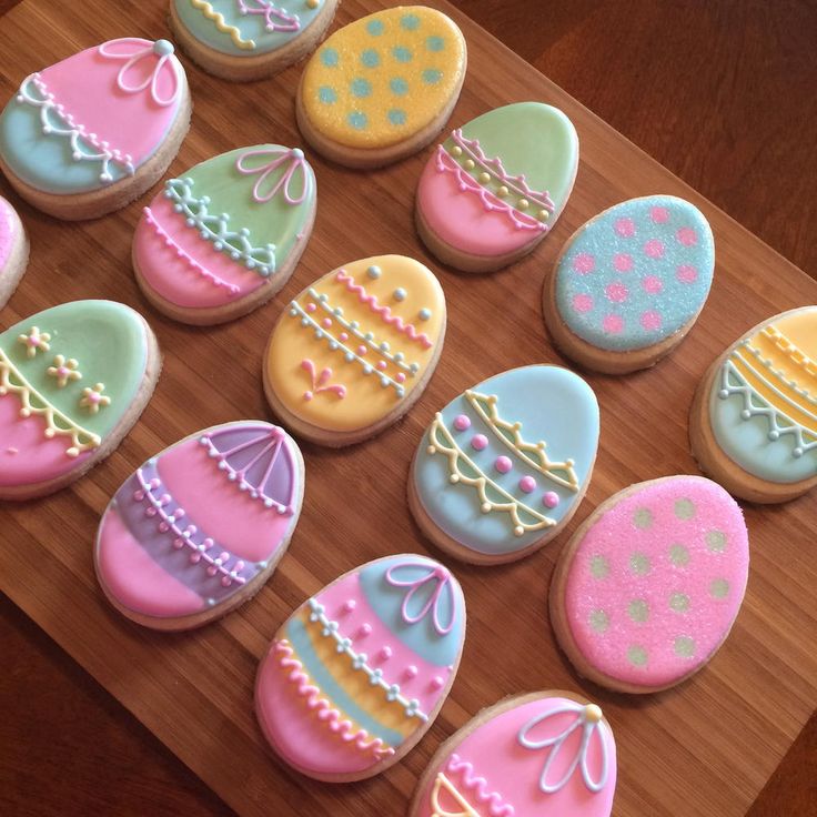 decorated cookies are arranged on a cutting board to be used as easter decorations for the table