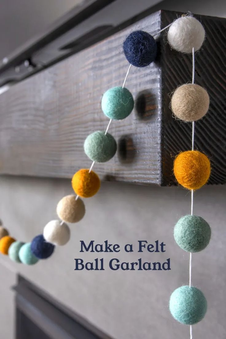 a felt ball garland hanging from a mantle with the words make a felt ball garland on it