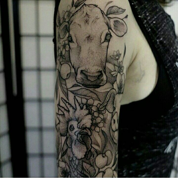 a woman's arm with a cow and flowers tattoo design on the left sleeve