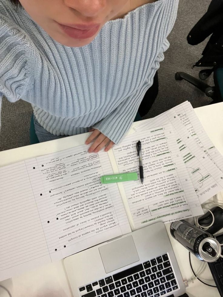 a person sitting at a desk with a laptop and papers on it, looking down