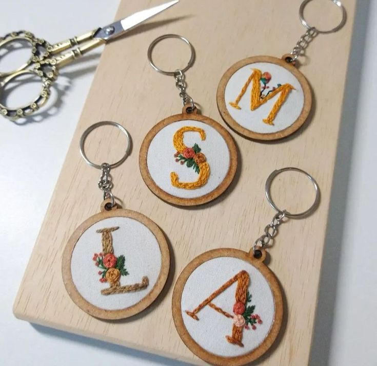 four embroidered keychains with the letter s on them and scissors next to it