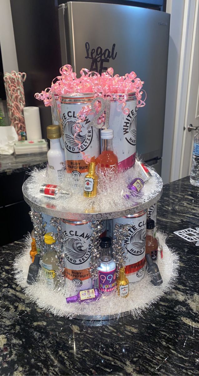 a cake made to look like an ice bucket with liquor bottles on top and pink flowers in the middle