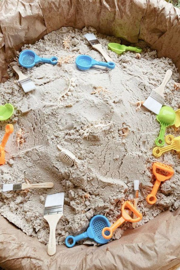 a sandbox filled with lots of toys like scissors, combs and hairbrushes