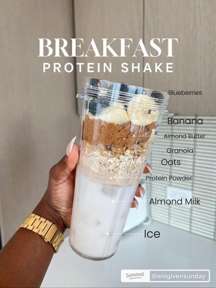 a woman holding up a cup filled with ice cream and granola on top of it