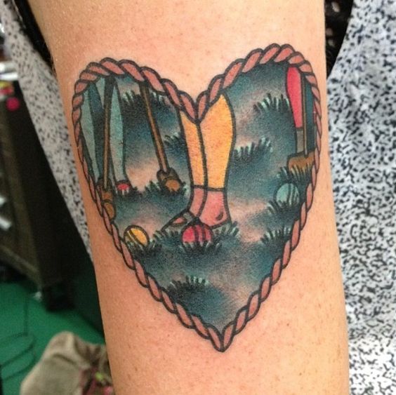 a woman's arm with a heart shaped tattoo on it, which has an image of two people holding hands