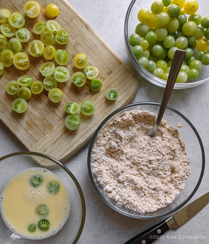 the ingredients for this recipe include grapes, flour, and olives on a cutting board