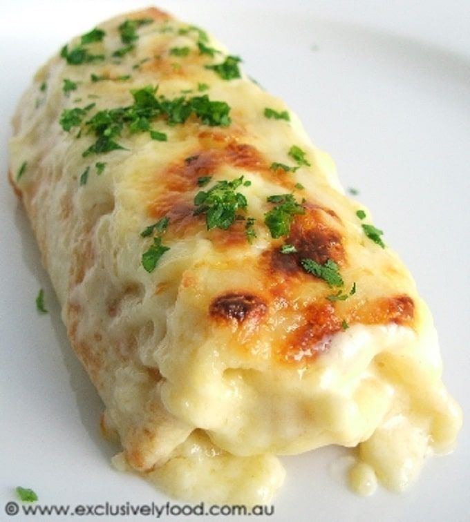 a white plate topped with cheesy bread covered in cheese and green garnish