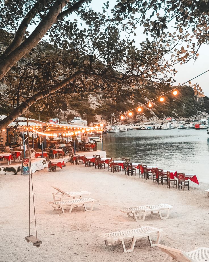 tables and chairs are set up on the beach for an outdoor dining area at dusk