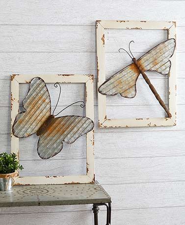 two metal butterflies mounted to the side of a white wall next to a small table