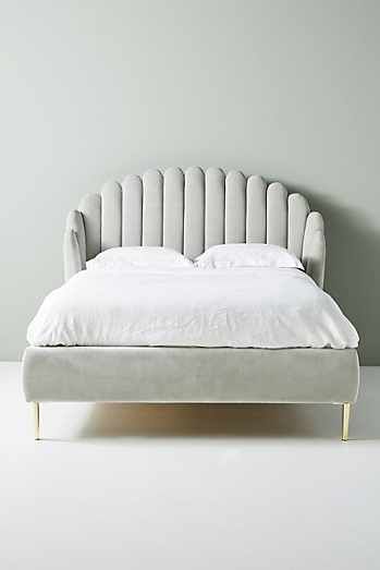 a white bed with an upholstered headboard and foot board in front of a gray wall