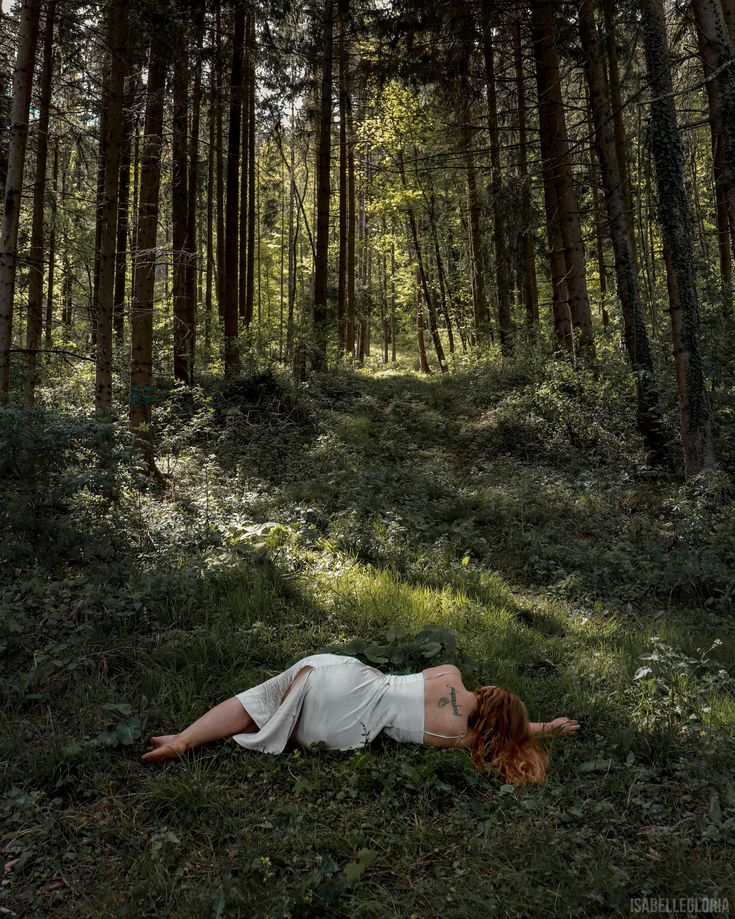 a woman laying on the ground in front of trees