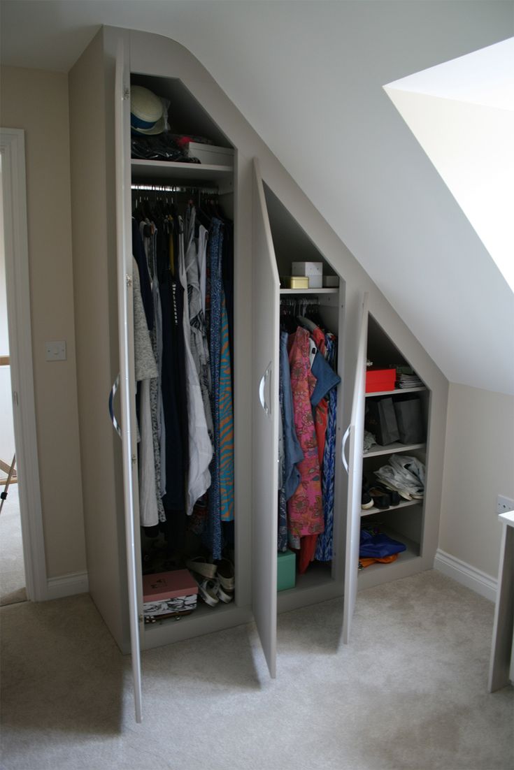 an attic bedroom with two closets full of clothes