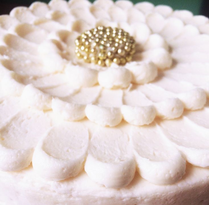 a close up view of a cake with white frosting and gold decorations on top