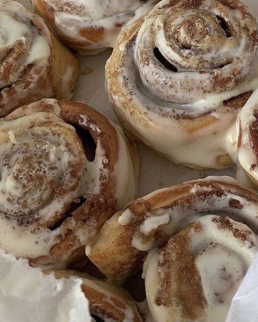 cinnamon rolls with icing sitting on top of each other