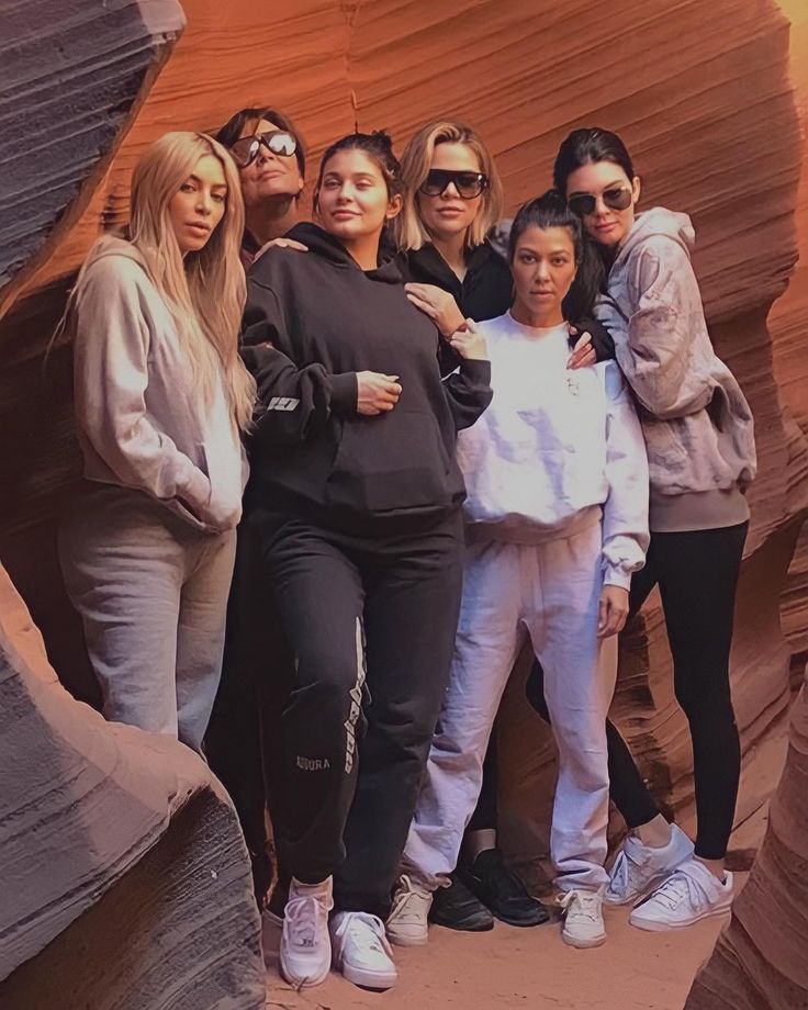 a group of women standing next to each other in front of a rock formation with their arms around one another