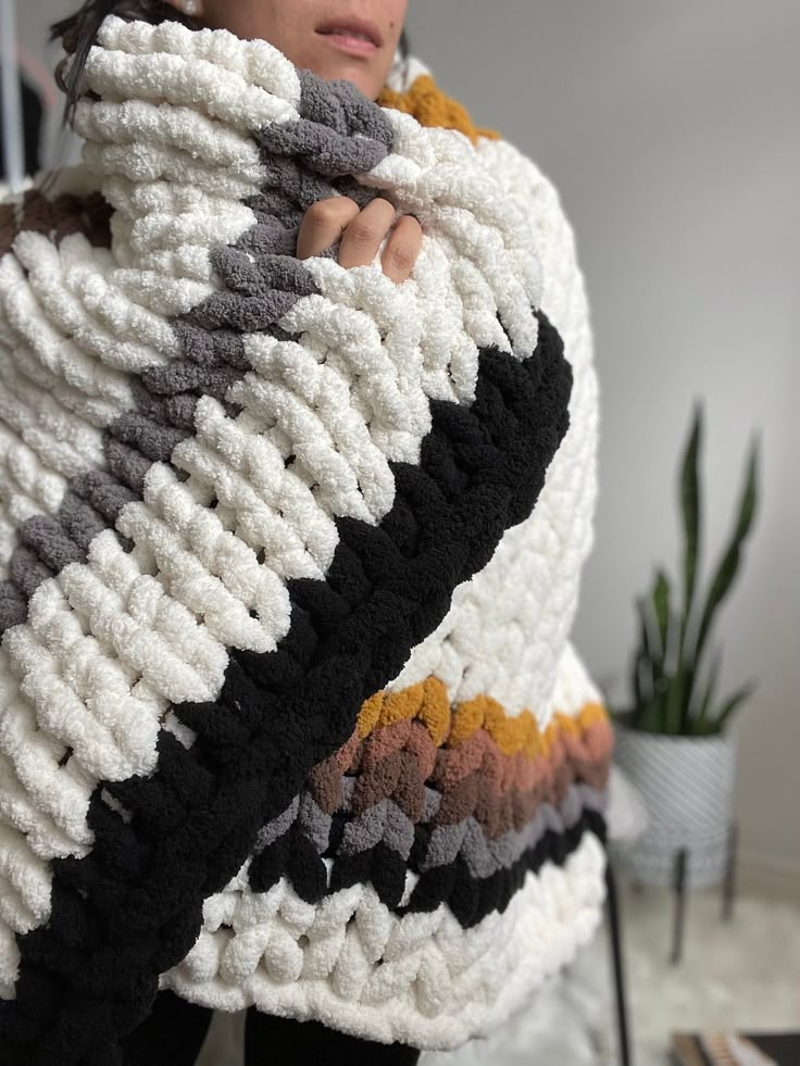 a woman is wrapped up in a crochet blanket