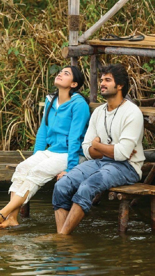 two people are sitting on a bench in the water looking up into the sky with their eyes closed