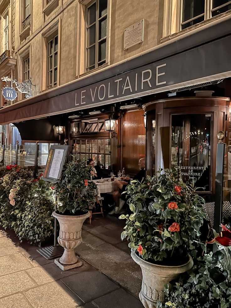 there are many potted plants on the sidewalk outside of this restaurant in paris, france