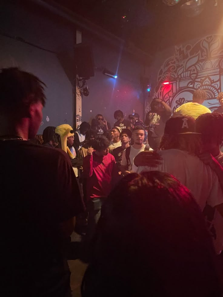 a group of people standing around each other in a room with lights on the ceiling