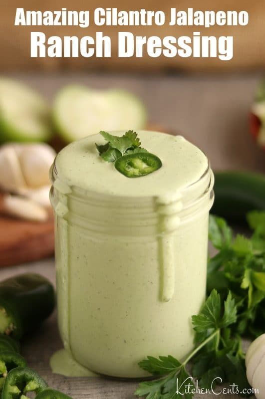 a jar filled with ranch dressing sitting on top of a table next to fresh vegetables