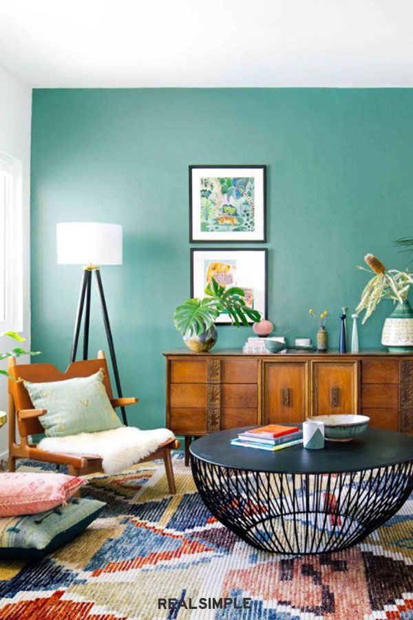 a living room filled with furniture and plants on top of a rug in front of a window