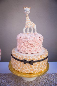 a giraffe on top of a cake with pink frosting