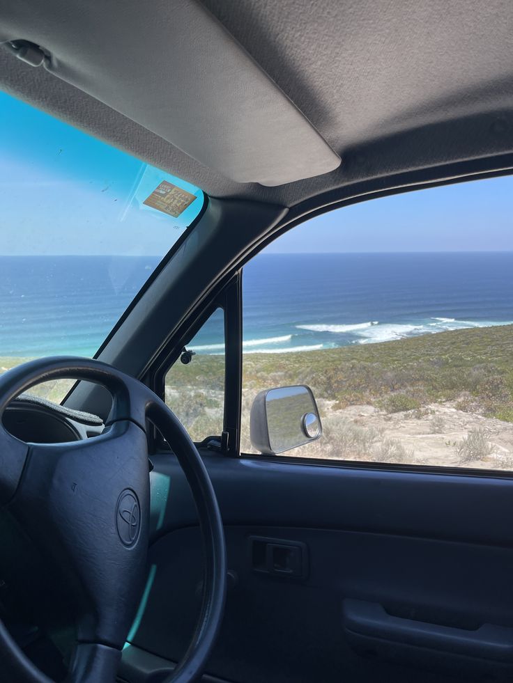 the view from inside a car looking out at the beach and ocean in the distance