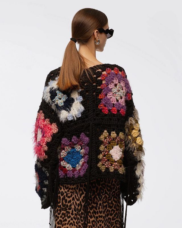 a woman wearing a black and multicolored knitted jacket with animal print details