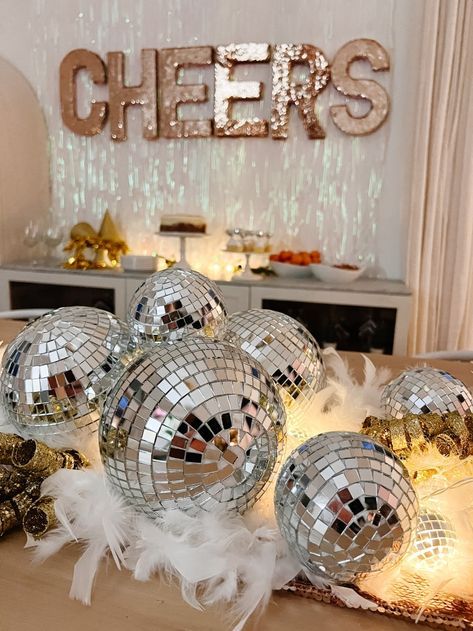 disco balls and feathers on a table in front of a sign that says chees