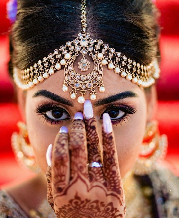 a woman with henna on her face and hands covering her eyes while looking at the camera