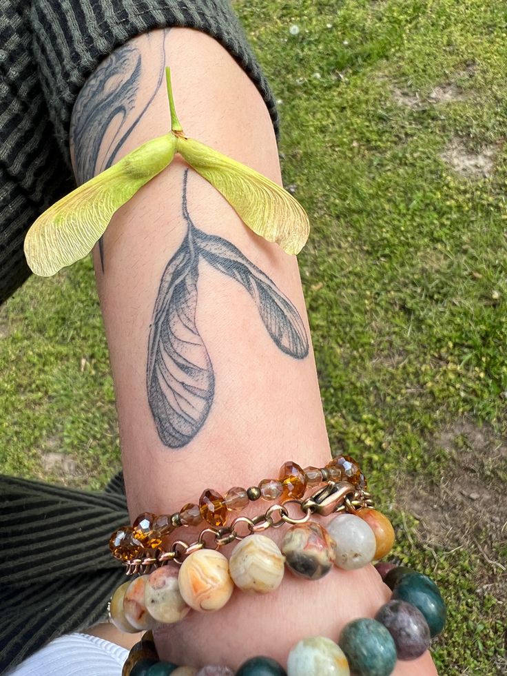 a woman's arm with several bracelets on it and a flower attached to the wrist