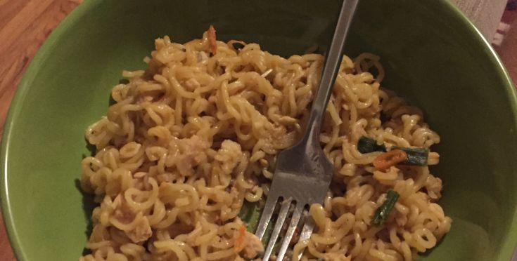 a green bowl filled with noodles and a fork