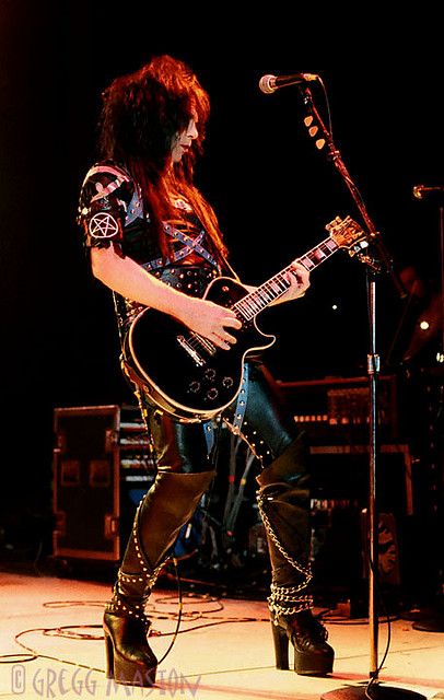 a man with long hair and boots playing guitar in front of a microphone on stage