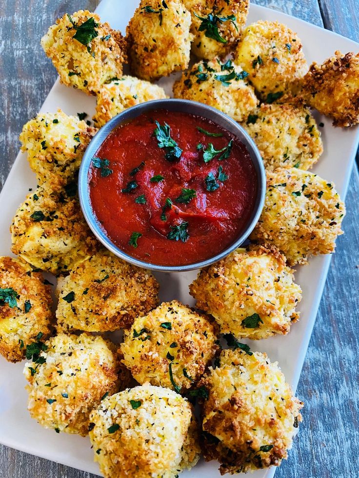 a white plate topped with tater tots next to a bowl of dipping sauce