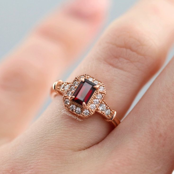 Gorgeous Vintage Inspired Garnet Ring ►Made of solid sterling silver with the 14k rose gold finish (925) ►Accented With Simulated Diamonds (CZ) ►Average band width: 2.3 mm ►Halo size: 9.9mm x 8.3mm Center Stone: Garnet Stone Cut: Emerald Measurements: 4.0 x 6.0 mm Carat Weight: 0.7 ct. (approx.) Gemstone creation: 100% Natural Hardness: 7.5 (Mohs scale) ►Average band width: 1.6 mm ►Please be aware that plated jewelry can wear off over time, if this is a concern we would suggest going with the st Classic 14k Rose Gold Ruby Ring For Anniversary, Classic Rose Gold Ruby Ring With Halo Setting, Classic Rose Gold Ruby Ring For Anniversary, Classic 14k Rose Gold Ruby Ring Gift, Classic Rose Gold Ruby Promise Ring, Classic Rose Gold Ruby Ring For Proposal, Classic Red Jewelry In 14k Rose Gold, Classic Red 14k Rose Gold Jewelry, Antique Promise Rings