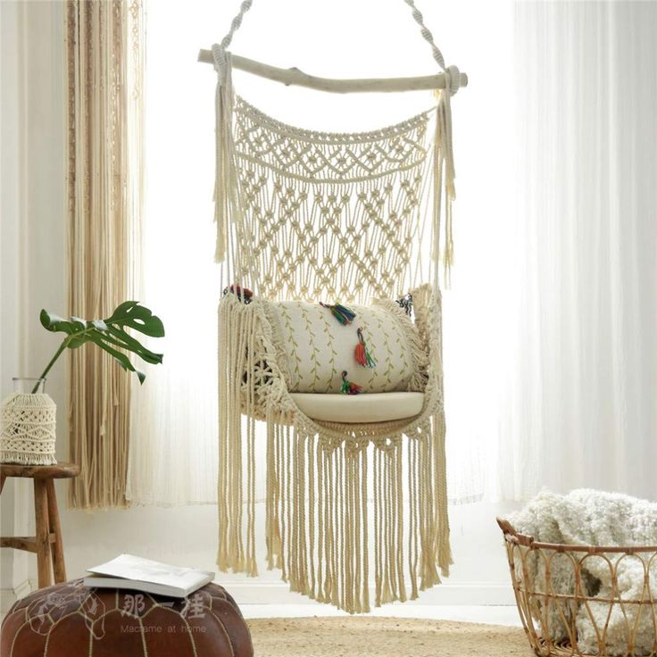 a white hammock hanging from the ceiling in a living room next to a window