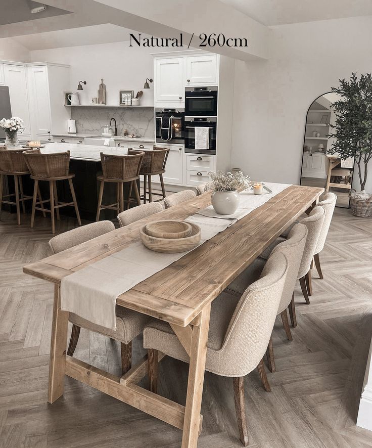 a dining room table with chairs and a bowl on top of it in front of an open kitchen area