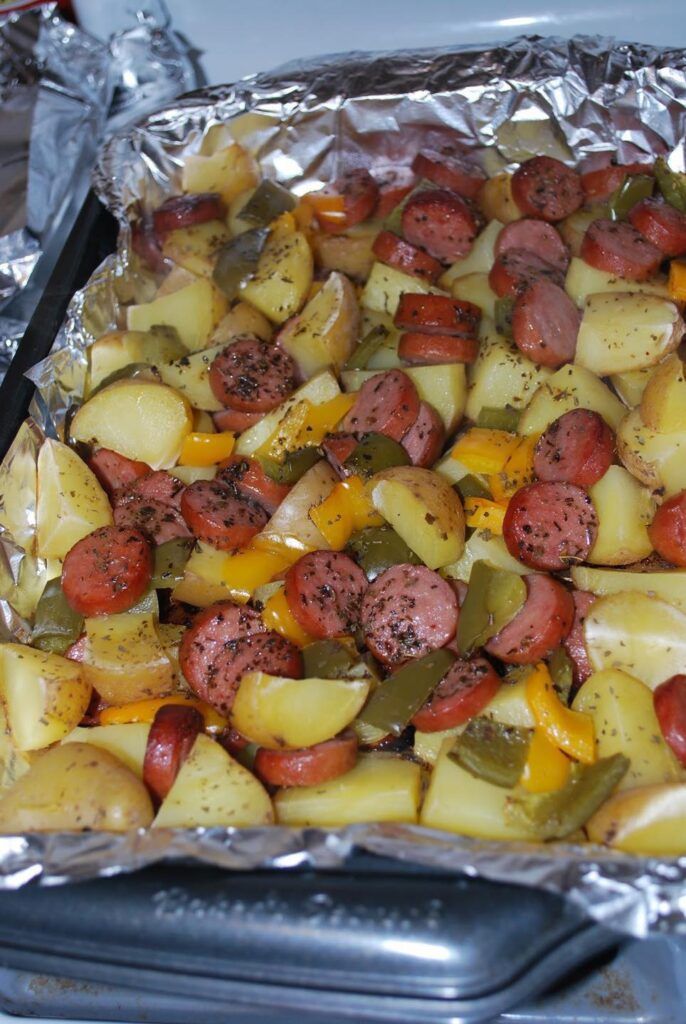 a pan filled with potatoes and sausages covered in tin foil