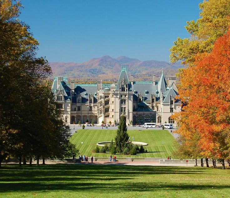 a large building with lots of windows in the middle of a field and trees around it