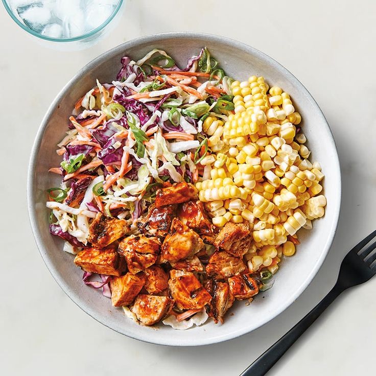 a white plate topped with corn, coleslaw and chicken