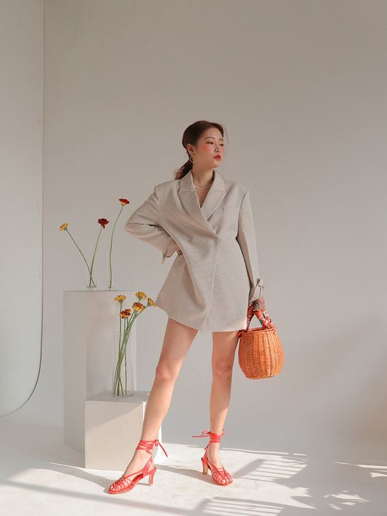 a woman standing next to a vase with flowers in it and holding a handbag