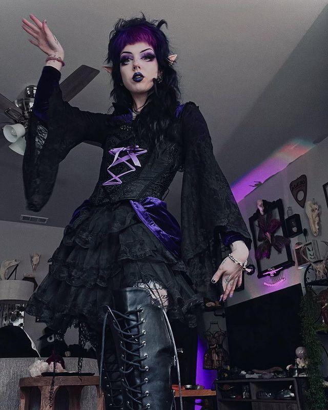 a woman dressed in black and purple is posing for the camera