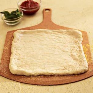 a cutting board with dough on it next to a bowl of fruit and sauces