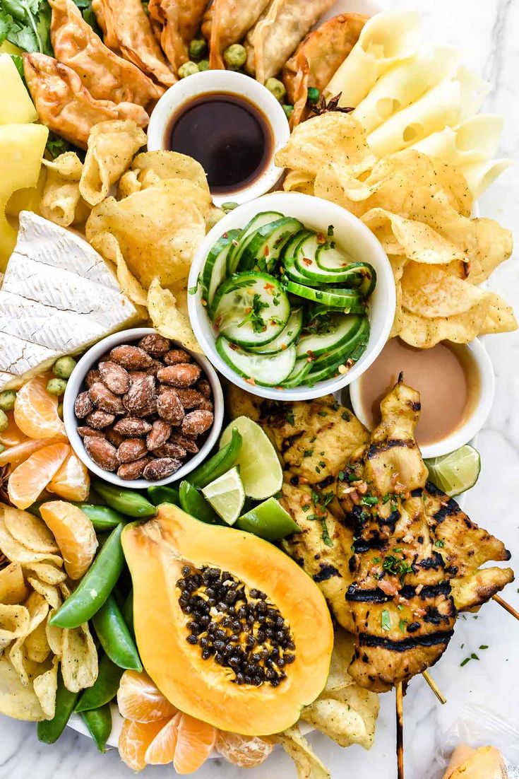 a platter filled with different types of food and dipping sauces on top of it